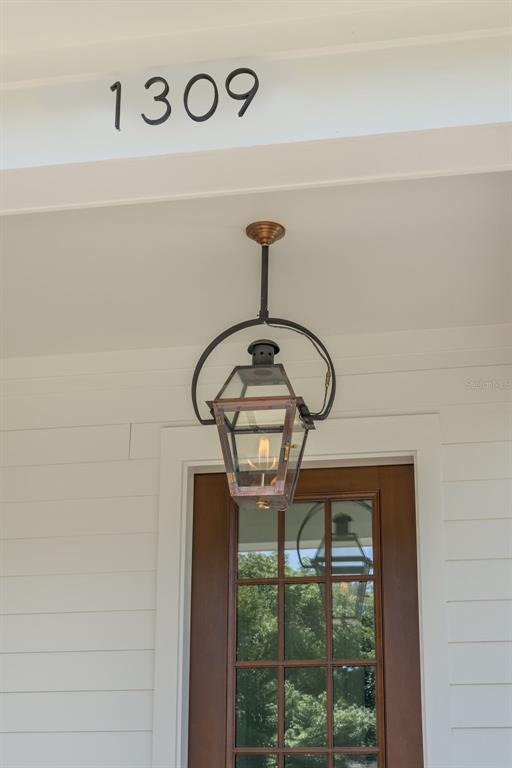 A hanging copper lantern illuminates the front porch above a wooden glass-paneled door — 1309 17TH AVENUE N, ST PETERSBURG, FL