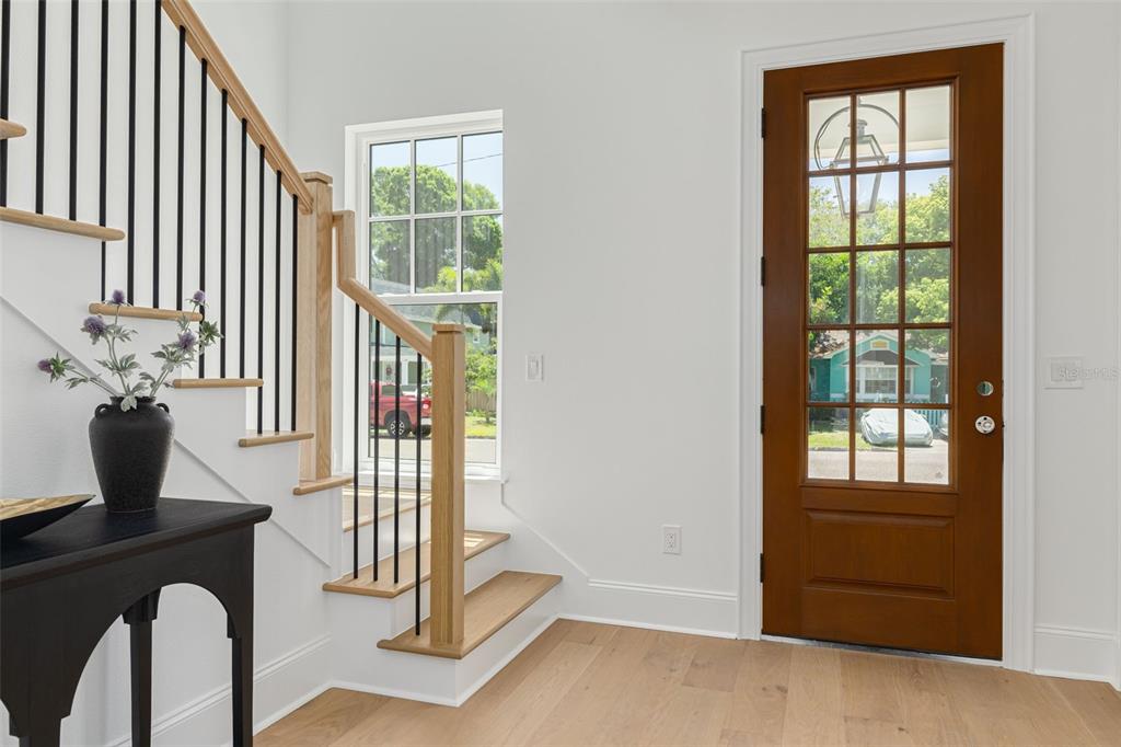 An entryway features a wooden front door, a staircase with black railings, and light wood flooring — 1309 17TH AVENUE N, ST PETERSBURG, FL