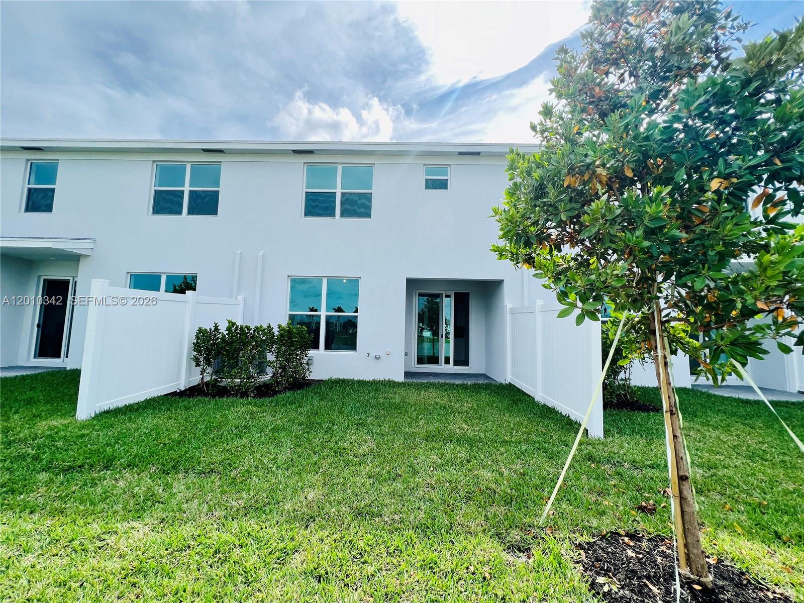 The exterior of a white two-story townhouse features a small backyard with a privacy fence — 6909 Harbours Edge Ave # 6909, Lake Worth FL 33467, LAKE WORTH, FL