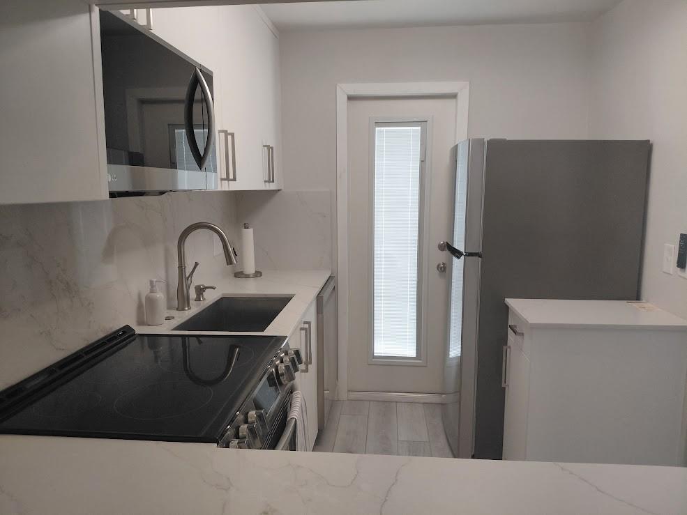 A modern kitchen features white cabinets, stainless steel appliances, and a marble-patterned backsplash — 1951 NE 39th Street # 127, Lighthouse Point FL 33064, LIGHTHOUSE POINT, FL