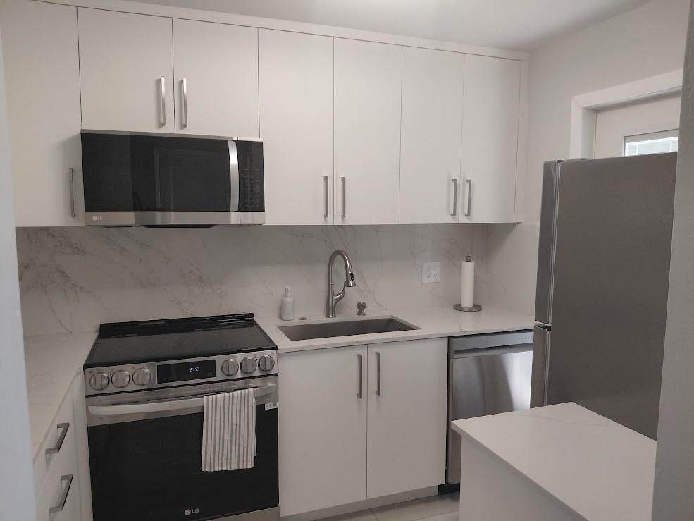 A modern kitchen features white cabinets, stainless steel appliances, and a marble-patterned backsplash — 1951 NE 39th Street # 127, Lighthouse Point FL 33064, LIGHTHOUSE POINT, FL