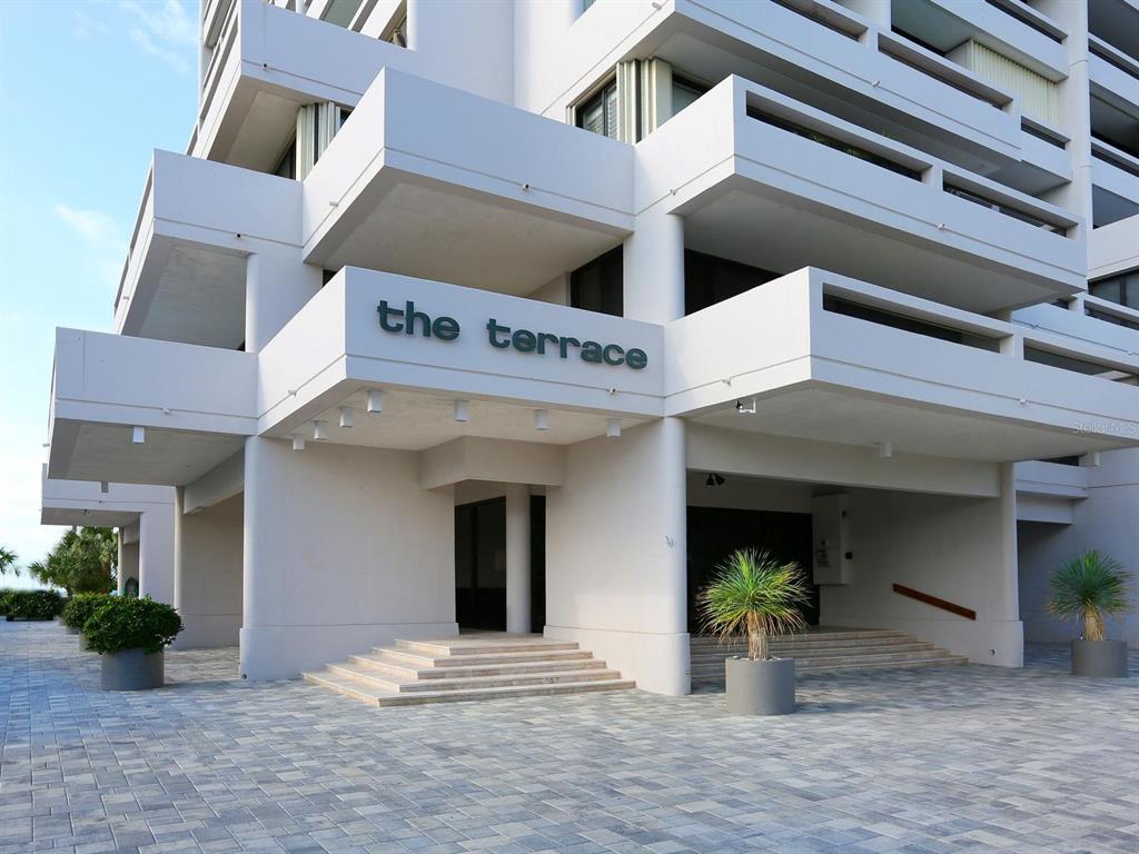The exterior of a white multi-story building features a sign reading the terrace — 5400 OCEAN BOULEVARD UNIT 5-3, SARASOTA, FL