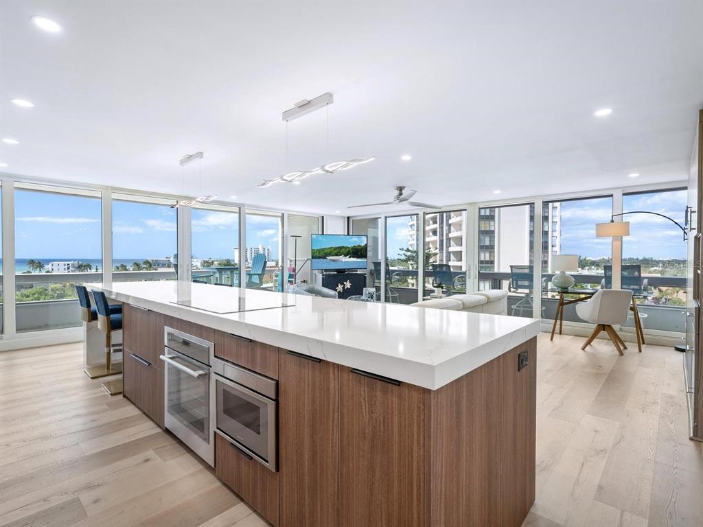 A modern kitchen island with white countertops and wood cabinetry overlooks a living area with ocean views — 5400 OCEAN BOULEVARD UNIT 5-3, SARASOTA, FL