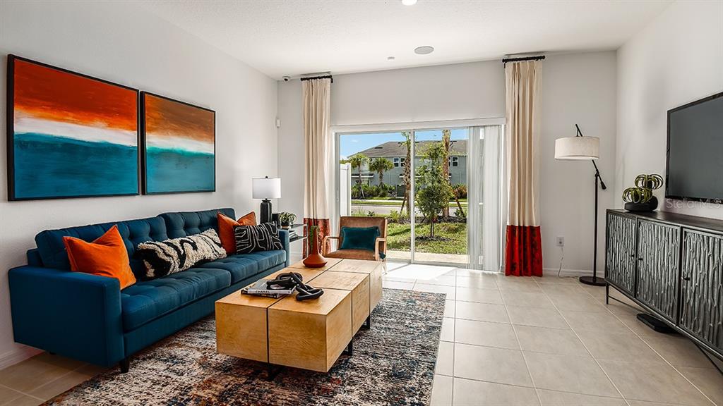A living room features a blue sofa, a wooden coffee table, and a sliding glass door — 10600 ORBIT TERRACE, SARASOTA, FL