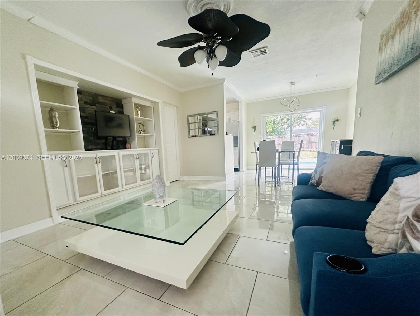 A living room features a blue sofa, a glass coffee table, and built-in shelving — 7021 Scott St., Hollywood FL 33024, HOLLYWOOD, FL