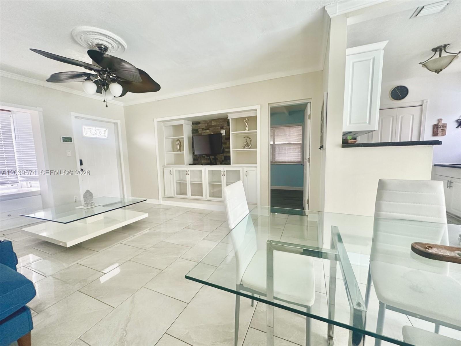 A living and dining area features white tile floors, a glass coffee table, and built-in shelving — 7021 Scott St., Hollywood FL 33024, HOLLYWOOD, FL
