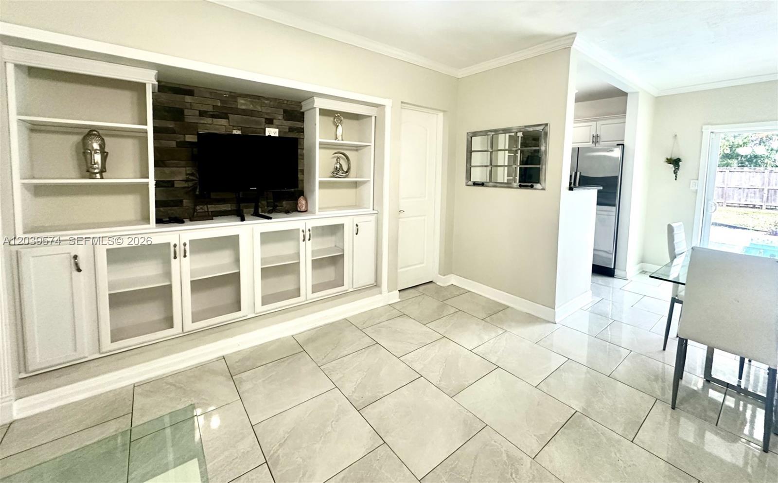 A living area features large light-colored floor tiles, a built-in entertainment unit, and dining space — 7021 Scott St., Hollywood FL 33024, HOLLYWOOD, FL