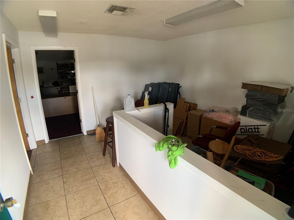 A room with tiled flooring, a half wall, and various boxes and office supplies — 6880 46TH AVENUE N, ST PETERSBURG, FL
