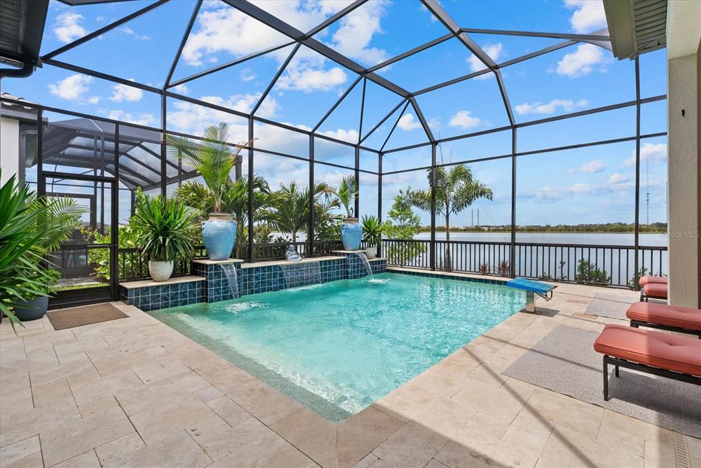 A screened-in pool area features a tiled water feature with blue pots and lake views — 556 BOCELLI DRIVE, NOKOMIS, FL