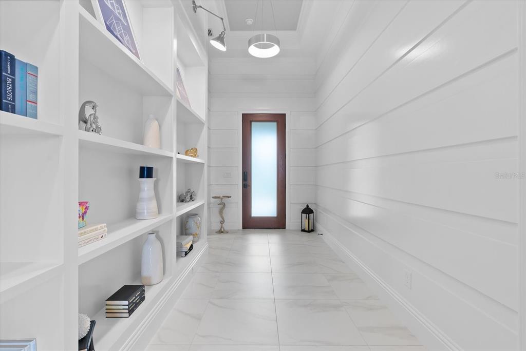A bright entryway features white shiplap walls, built-in shelving, and light-colored tile flooring — 556 BOCELLI DRIVE, NOKOMIS, FL