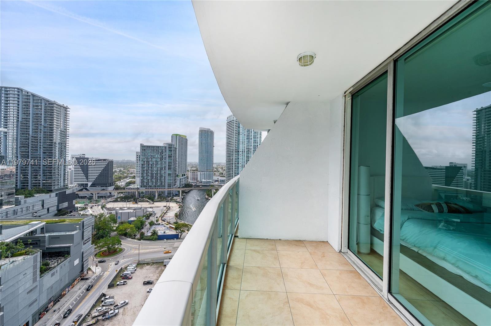 A high-rise balcony with tile flooring overlooks a city skyline and a river — 41 SE 5th St # 1508, Miami FL 33131, MIAMI, FL