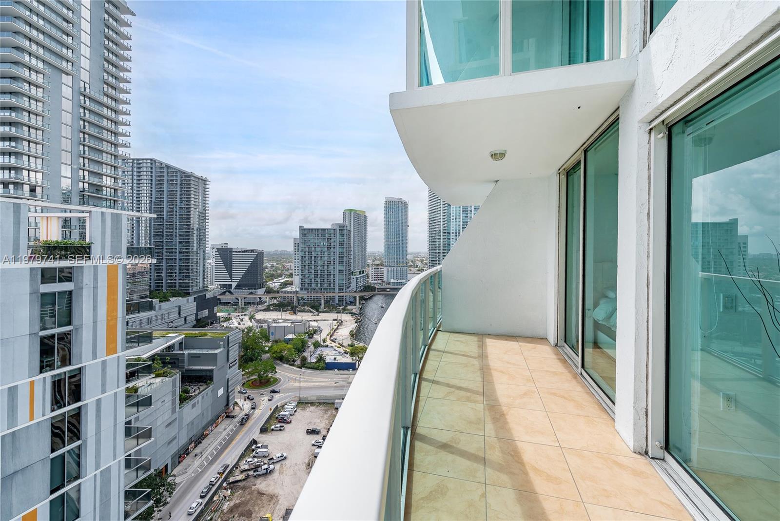 A high-rise balcony with tiled flooring overlooks a city skyline and a river — 41 SE 5th St # 1508, Miami FL 33131, MIAMI, FL