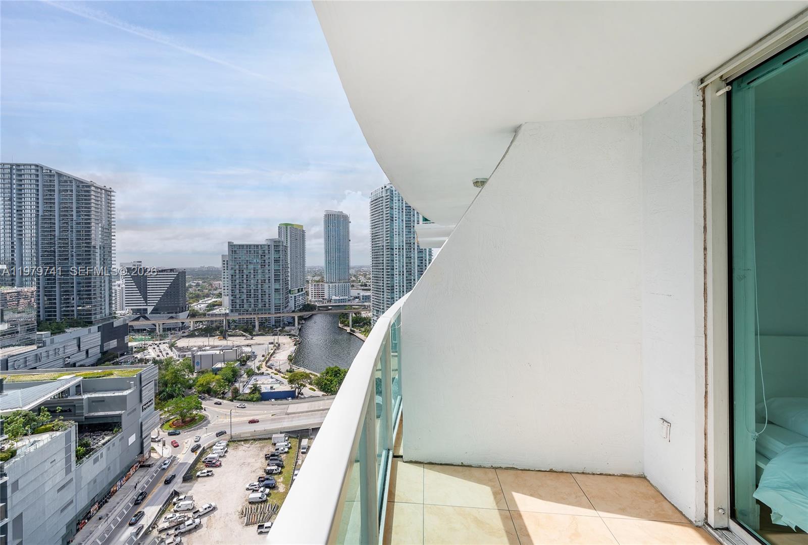 A high-rise balcony with a glass railing overlooks a city skyline and a river — 41 SE 5th St # 1508, Miami FL 33131, MIAMI, FL