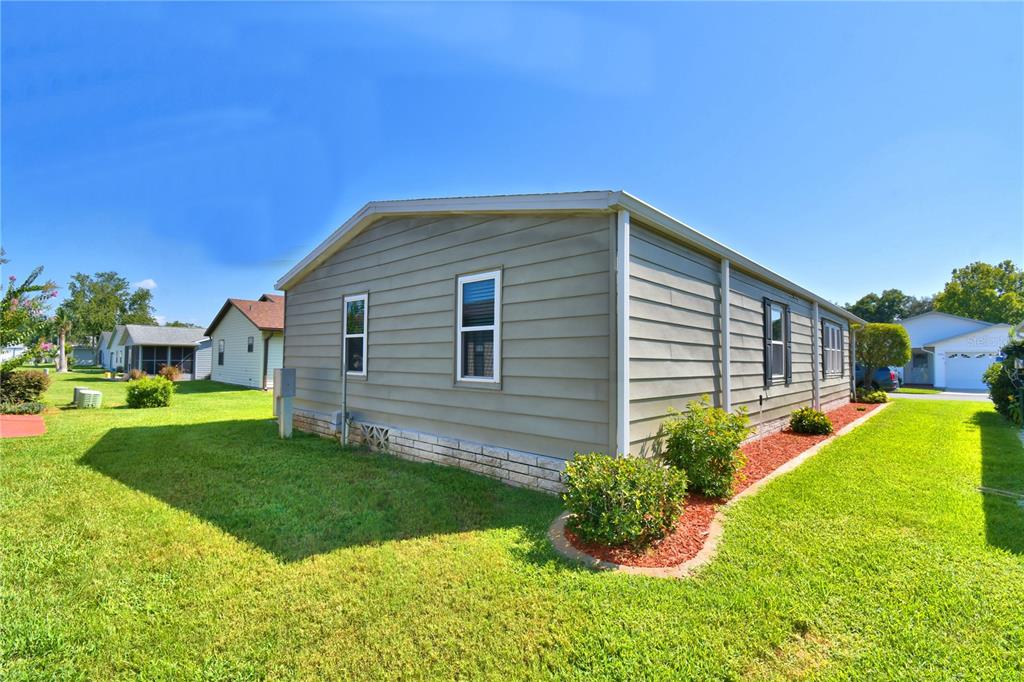 A side view of a single-story house with light green siding and a stone base — 4901 COLONNADES CIRCLE E, LAKELAND, FL