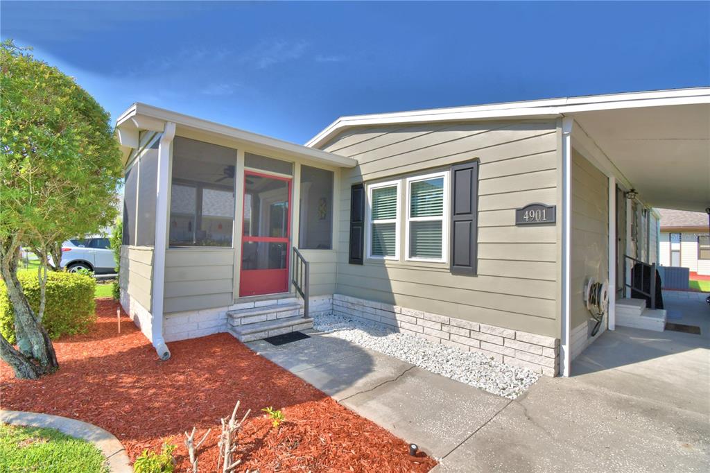 A single-story house with light green siding, a screened-in porch, and a covered carport — 4901 COLONNADES CIRCLE E, LAKELAND, FL