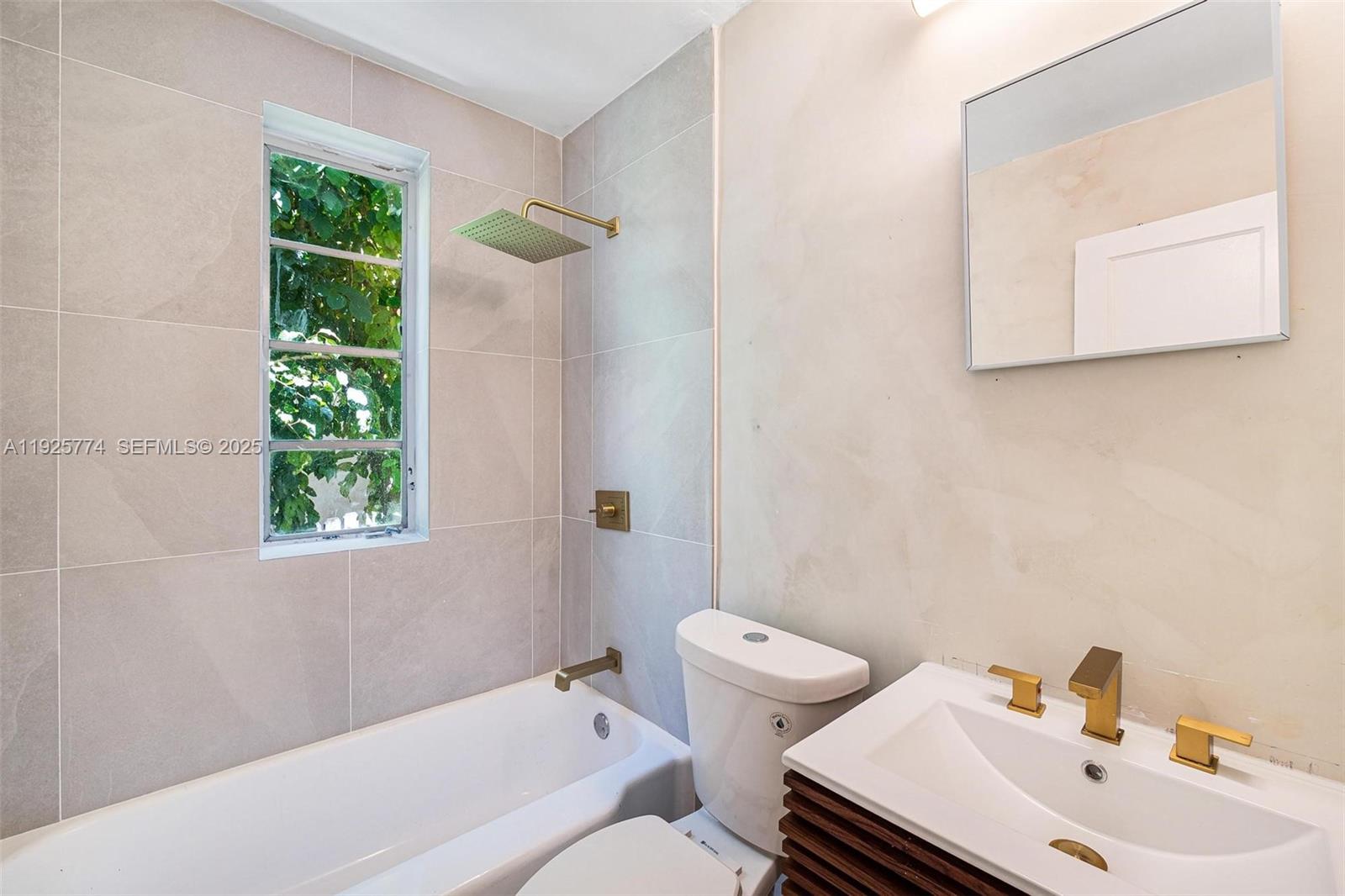 A bathroom features a bathtub with a shower, a toilet, and a vanity with gold fixtures — 1611 Euclid Ave # 8, Miami Beach FL 33139, MIAMI BEACH, FL