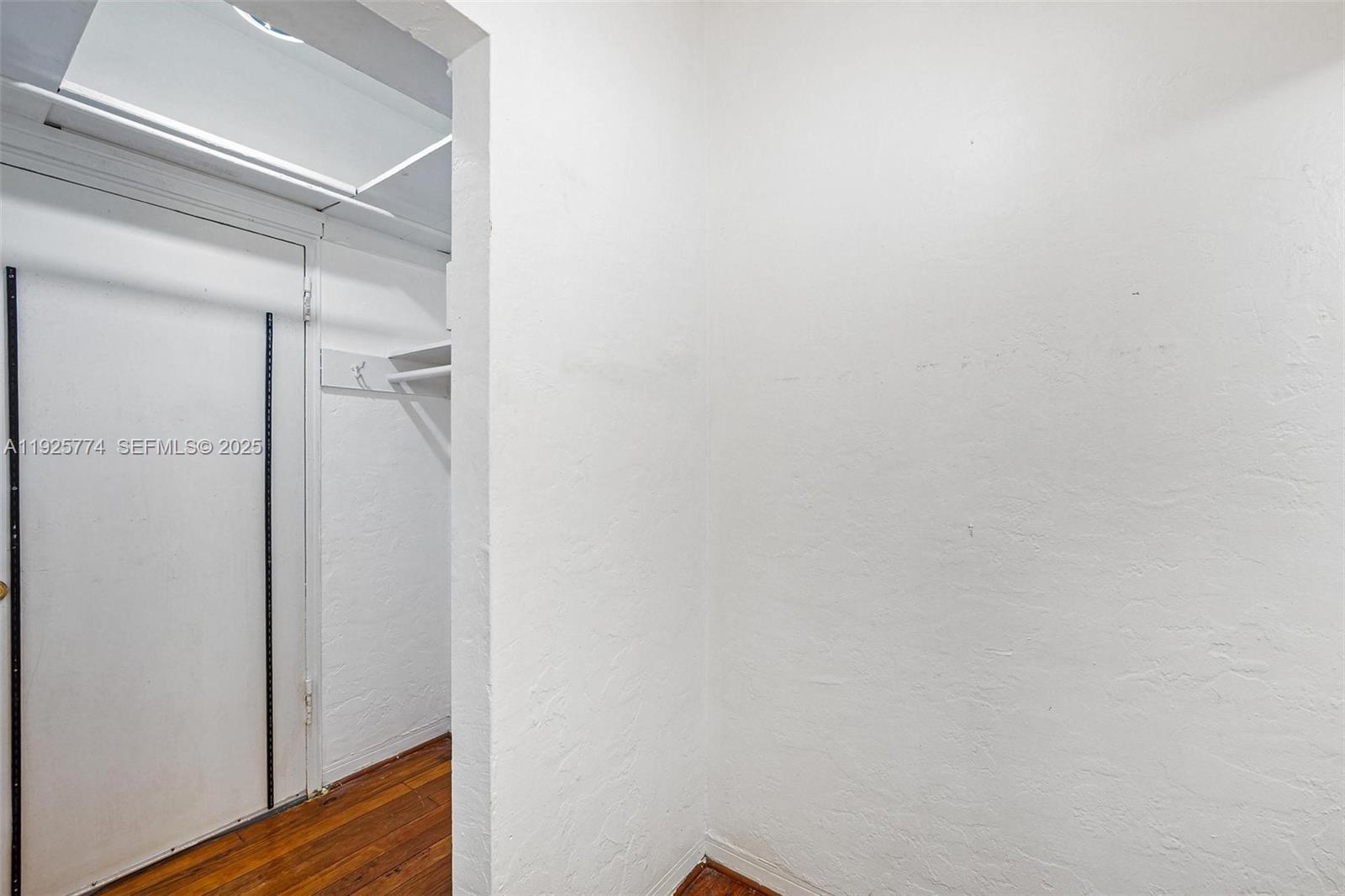 A small, white-walled closet space features a wooden floor and a white door — 1611 Euclid Ave # 8, Miami Beach FL 33139, MIAMI BEACH, FL