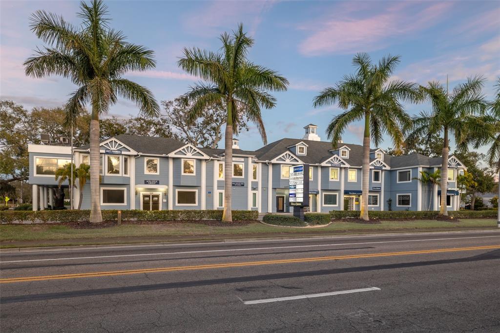 A two-story blue office building with palm trees stands along a paved road at dusk — 1465 S FORT HARRISON AVENUE, CLEARWATER, FL