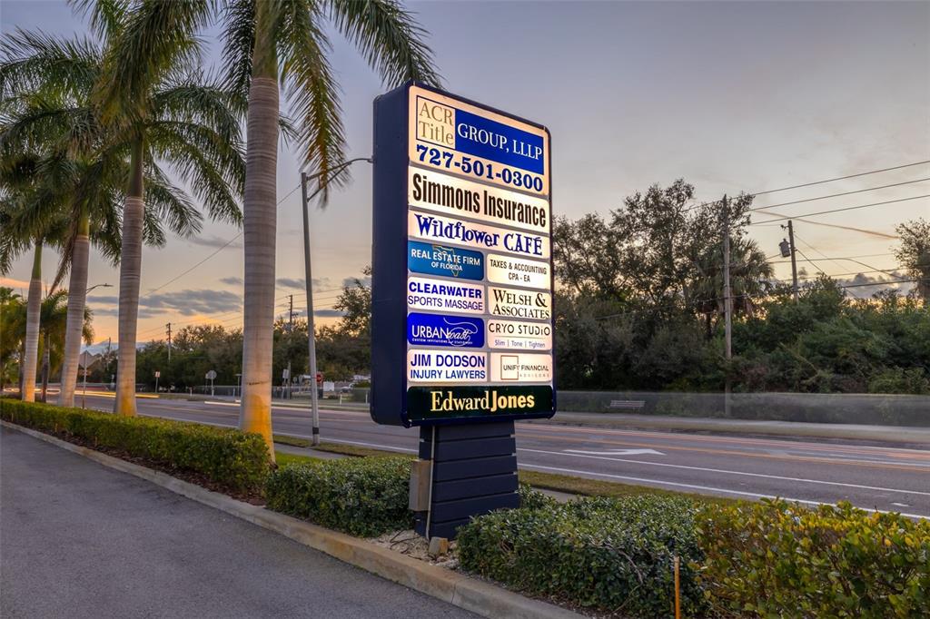 A tall, illuminated business directory sign stands beside a road lined with palm trees — 1465 S FORT HARRISON AVENUE, CLEARWATER, FL