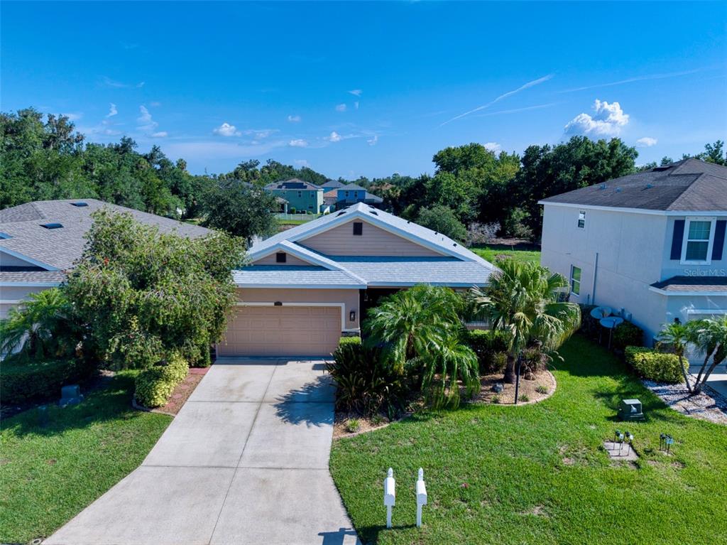 An exterior view of a single-story suburban house with a concrete driveway and palm trees — 5710 BROAD RIVER RUN, ELLENTON, FL