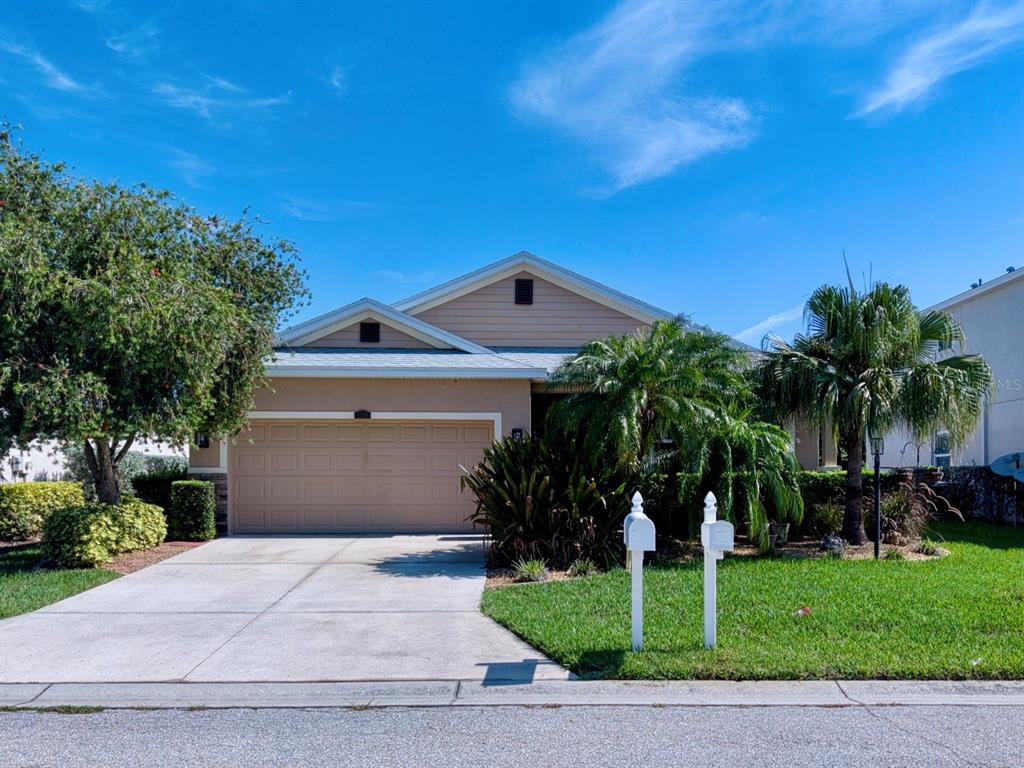 A single-story house with a beige exterior, a two-car garage, and a front lawn — 5710 BROAD RIVER RUN, ELLENTON, FL