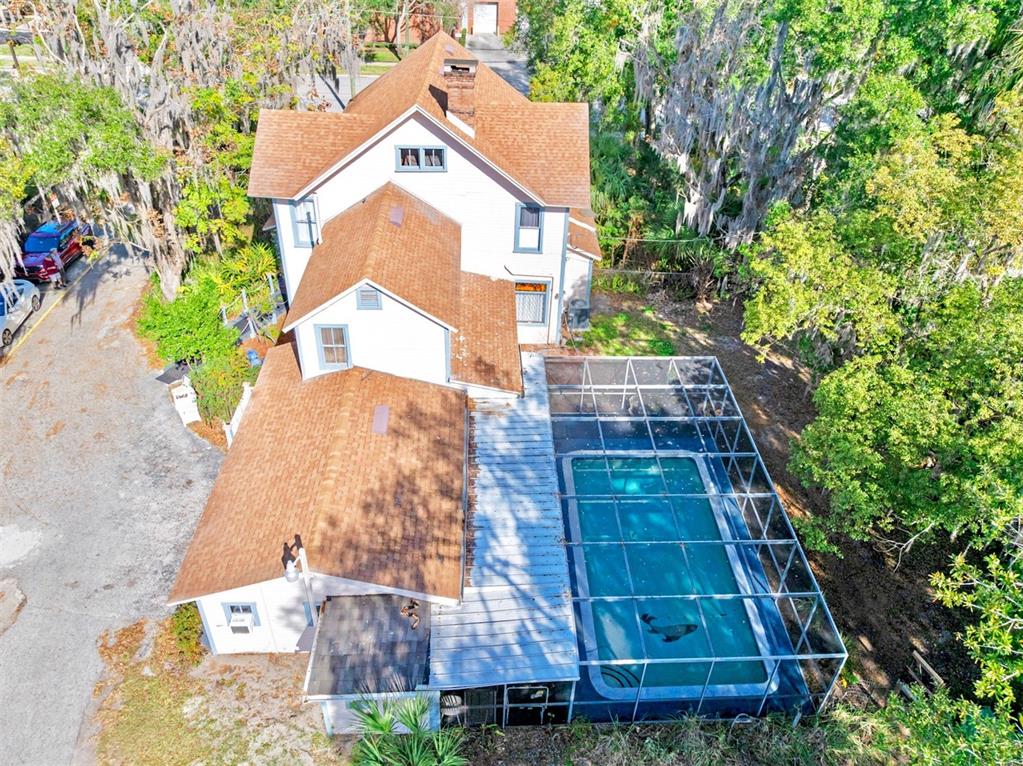 An aerial view of a multi-story house with a screened-in swimming pool and driveway — 228 W HOWRY AVENUE, DELAND, FL