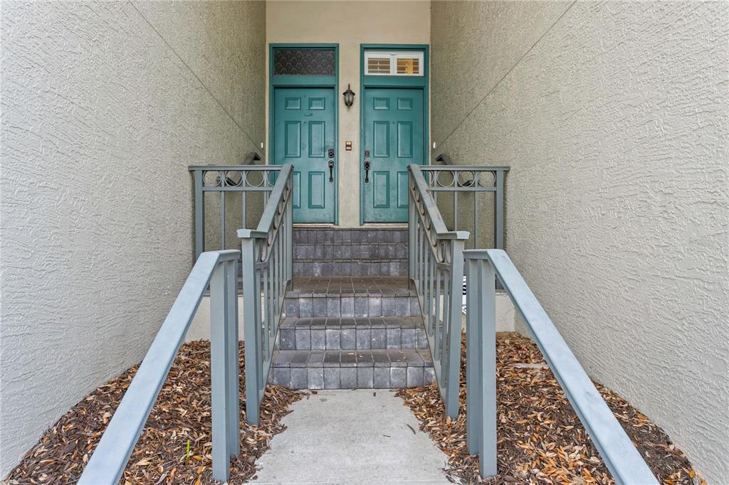 A concrete walkway leads to a set of stairs between two teal front doors — 751 CORAL REEF DRIVE, TAMPA, FL