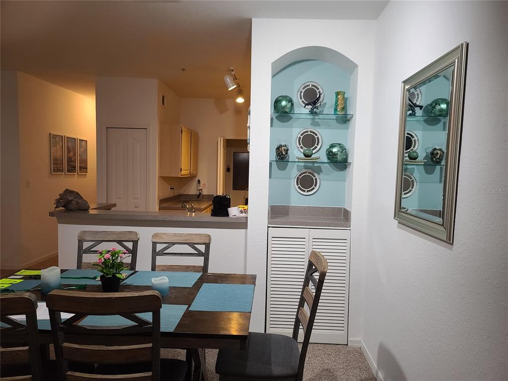 A dining area features a wooden table, chairs, and a built-in arched display niche — 8908 LEGACY COURT UNIT 104, KISSIMMEE, FL