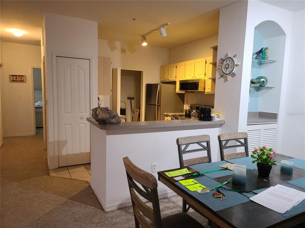 A kitchen with light cabinets and a breakfast bar overlooks a dining area with chairs — 8908 LEGACY COURT UNIT 104, KISSIMMEE, FL