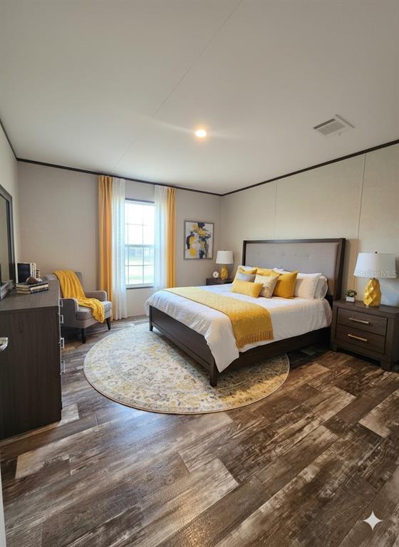A bedroom features a king bed, wood-look flooring, yellow accents, and a corner armchair — 12070 NE 63RD PLACE, WILLISTON, FL