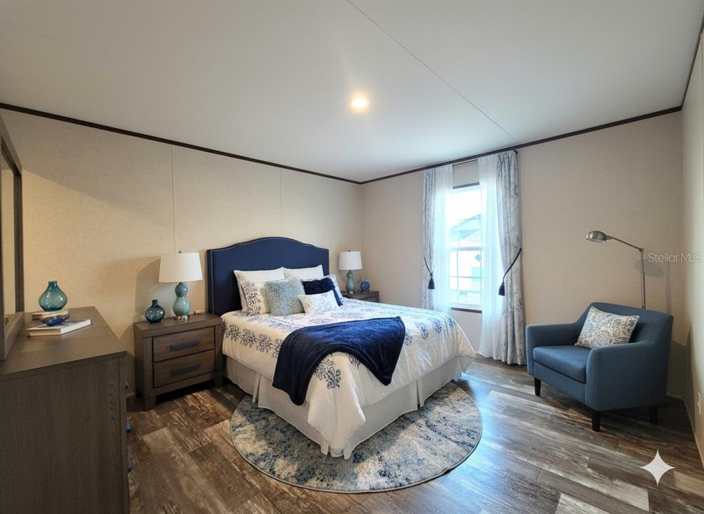 A bedroom features a blue upholstered headboard, a patterned rug, and a matching armchair — 12070 NE 63RD PLACE, WILLISTON, FL