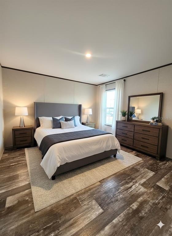A bedroom features a gray upholstered bed, matching nightstands, a dresser with a mirror, and wood-look flooring — 12070 NE 63RD PLACE, WILLISTON, FL