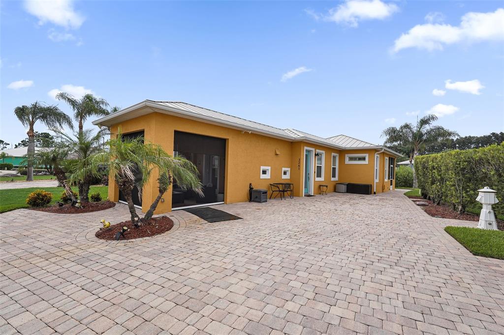 A yellow house with a paver driveway and a screened-in porch under a blue sky — 3261 FISH HAWK DRIVE, POLK CITY, FL