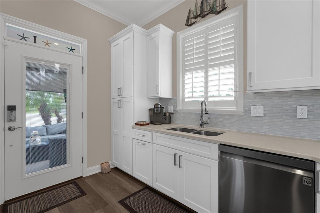 A kitchen features white cabinets, a stainless steel dishwasher, a sink, and a glass-paneled door — 3261 FISH HAWK DRIVE, POLK CITY, FL
