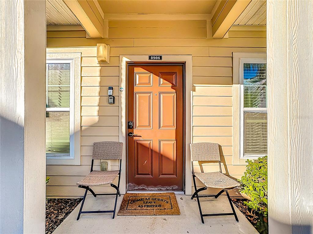 A front entryway features a brown door, two wicker chairs, and a welcome mat — 8986 SHINE DRIVE, KISSIMMEE, FL