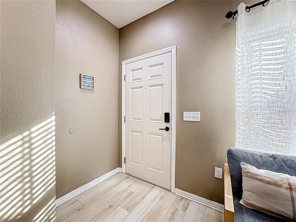 An entryway features a white door, light wood-look flooring, and tan walls — 8986 SHINE DRIVE, KISSIMMEE, FL