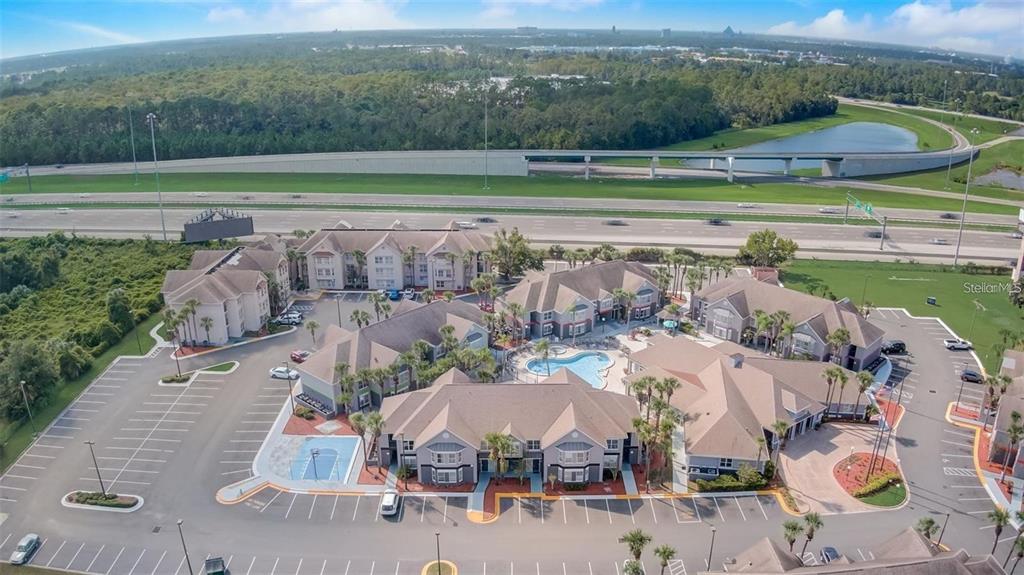 An aerial view shows a multi-building apartment complex with a central pool and parking lots — 3100 PARKWAY BOULEVARD UNIT 737, KISSIMMEE, FL