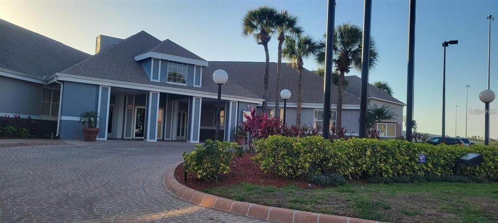 A paved driveway leads to the entrance of a gray building with palm trees — 3100 PARKWAY BOULEVARD UNIT 737, KISSIMMEE, FL
