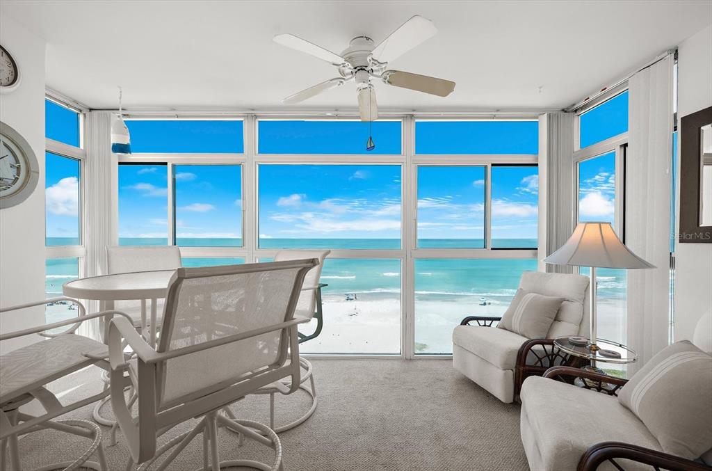 A sunroom with a dining set and lounge chair overlooks a sandy beach and ocean — 255 THE ESPLANADE N UNIT 701, VENICE, FL