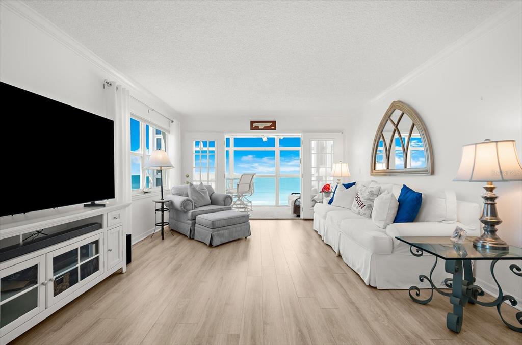 A living room features light wood flooring, a white sofa, and a view of the ocean — 255 THE ESPLANADE N UNIT 701, VENICE, FL