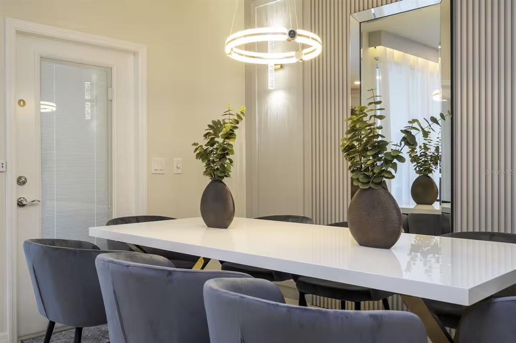 A dining room features a white table, grey velvet chairs, and a modern circular chandelier — 4294 LANA AVENUE, DAVENPORT, FL
