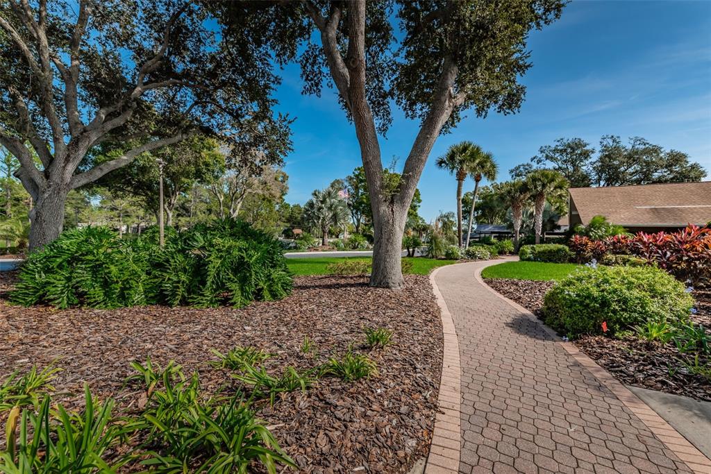 A living room with a large television, gray sofa, and an adjacent dining area — 2735 SHERBROOKE LANE UNIT C, PALM HARBOR, FL