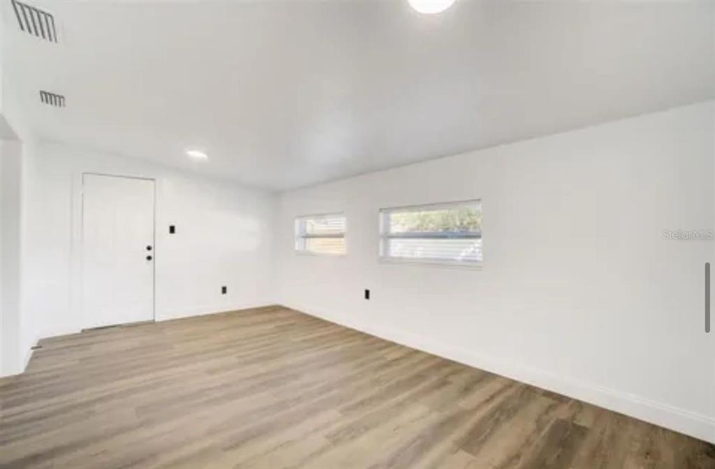 An empty room with white walls, light wood-look flooring, and two windows — 5205 CHENAULT AVENUE, ORLANDO, FL