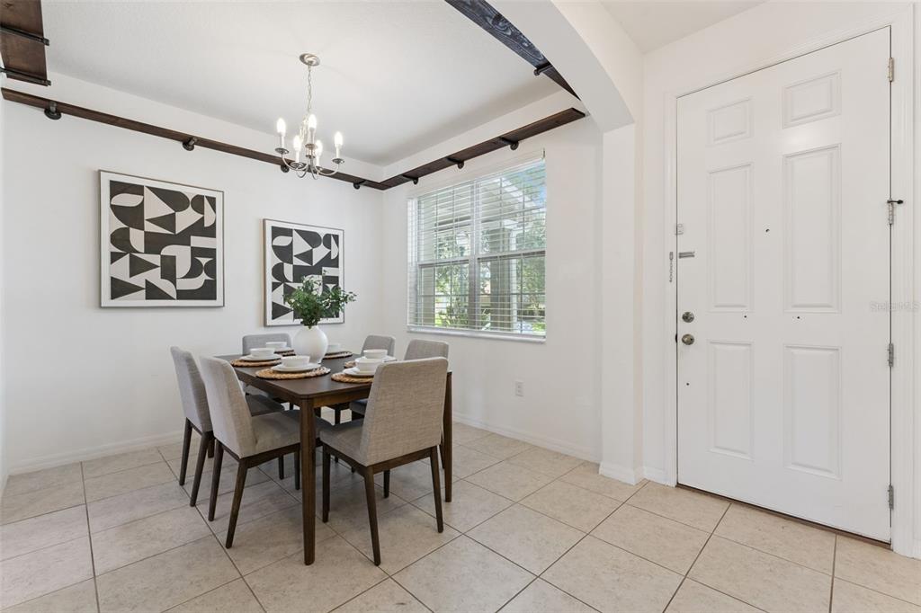 A dining room with a wooden table, six chairs, and dark wood ceiling beams — 7988 EDGEWOOD FOREST DRIVE, ORLANDO, FL