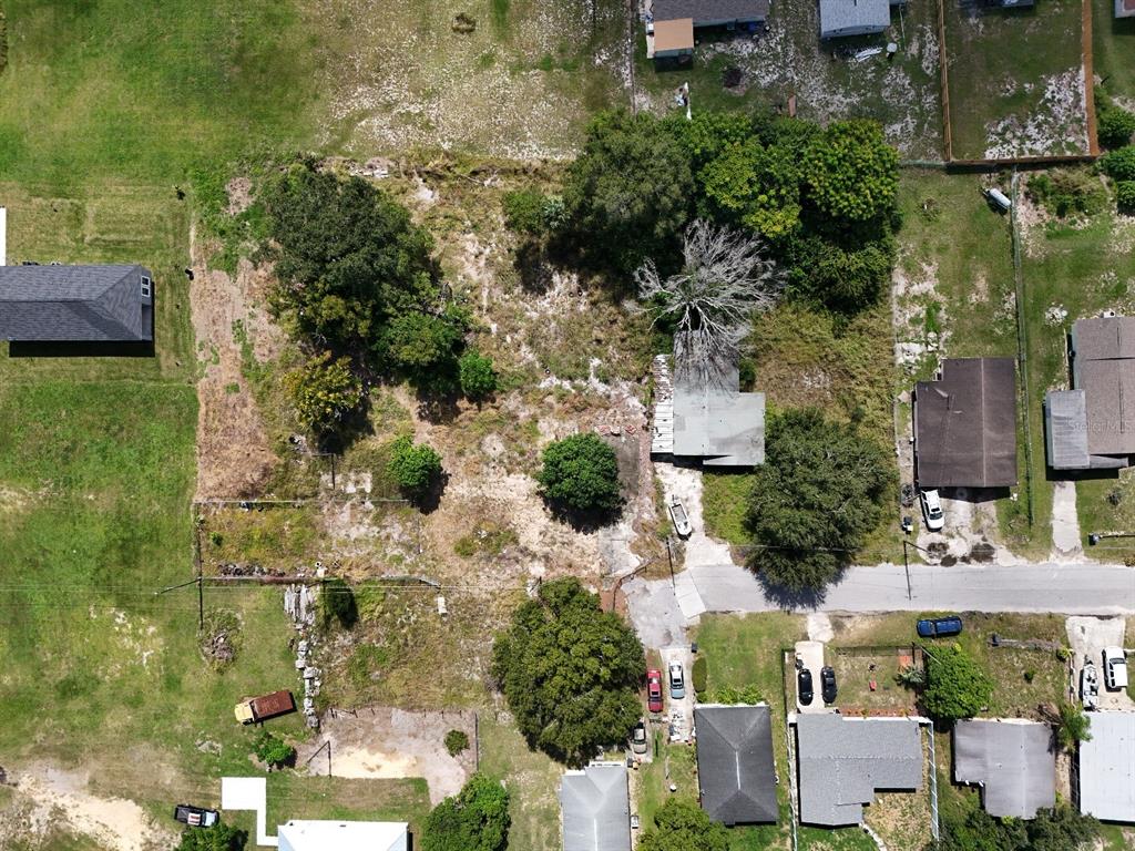 An aerial view shows a vacant lot with trees and vegetation next to residential houses — 219 SHEILA LANE, LAKE WALES, FL