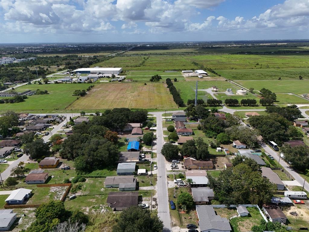 An aerial view shows a residential neighborhood bordering large open fields and industrial buildings — 219 SHEILA LANE, LAKE WALES, FL