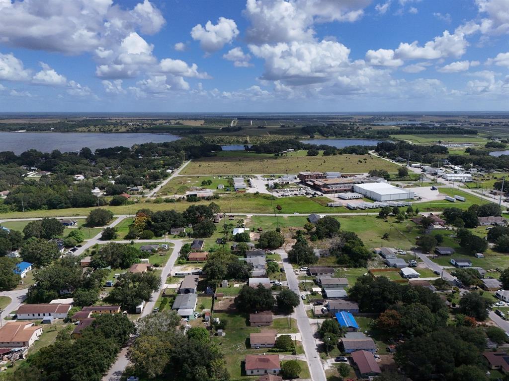 Aerial view of a residential neighborhood with scattered houses, trees, and a nearby industrial facility — 219 SHEILA LANE, LAKE WALES, FL
