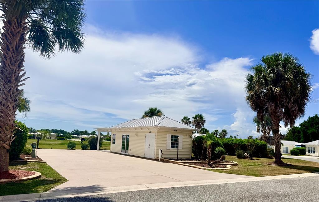 A light-colored exterior building with a metal roof sits on a large concrete lot — 9444 SE 49TH TERRACE, WEBSTER, FL