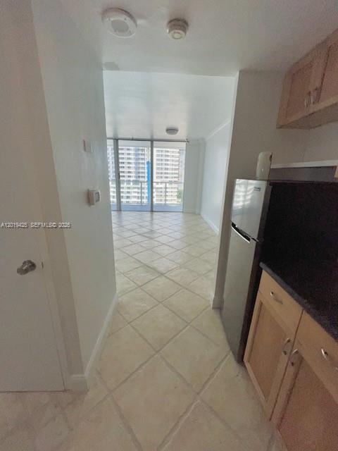 A tiled hallway leads to a kitchen with wooden cabinets and a view of buildings — 3301 NE 5th Ave # 1112, Miami FL 33137, MIAMI, FL
