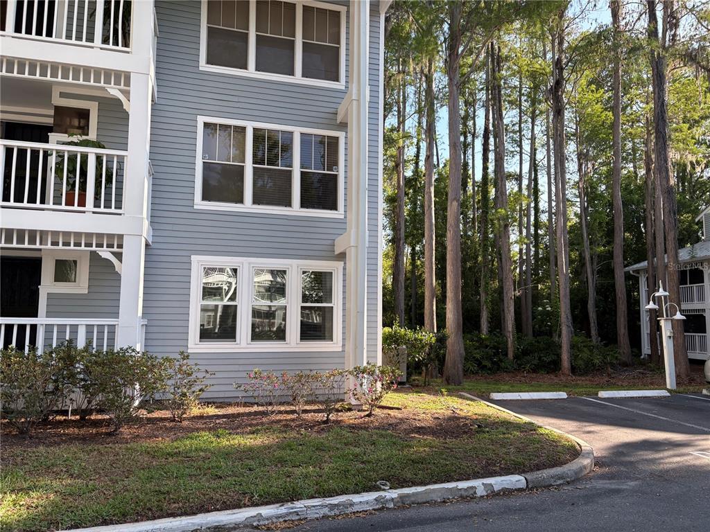 The exterior of a multi-story building with gray siding, white trim, and a parking area — 2511 2511 DOLLY BAY DRIVE UNIT 102, PALM HARBOR, FL